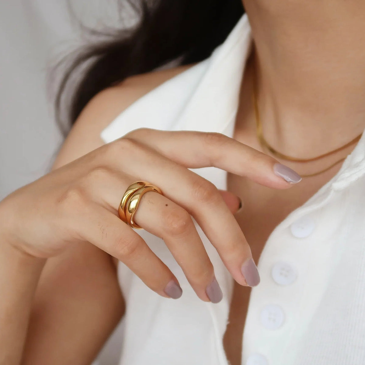 Close-up of a hand wearing a gold ring with a blurred background