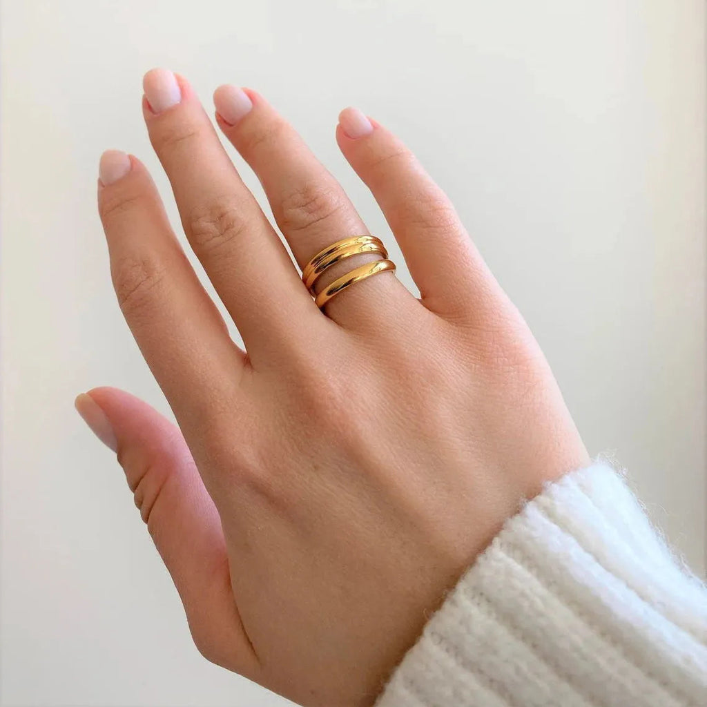 Hand wearing a gold ring on a plain background